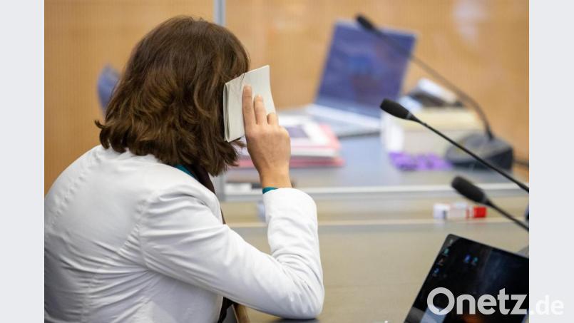 Eine wegen Mordes angeklagte Frau hält sich zu Prozessbeginn im Landgericht Regensburg ein Blatt vors Gesicht. Die 25-Jährige hatte im Dezember 2020 ihr neugeborenes Kind in einer Mülltonne abgelegt. Bild: Daniel Karmann/dpa