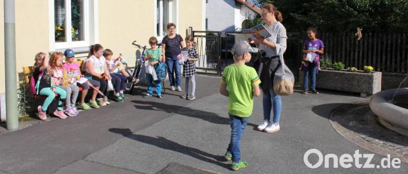 Eva Gruber (stehend mit Buch) las den begeisterten Kindern an jeder Station der Leseschnitzeljagd ein Kapitel aus dem Buch „Ein kleiner Hase fliegt rund um die Welt“ vor. Bild: fks