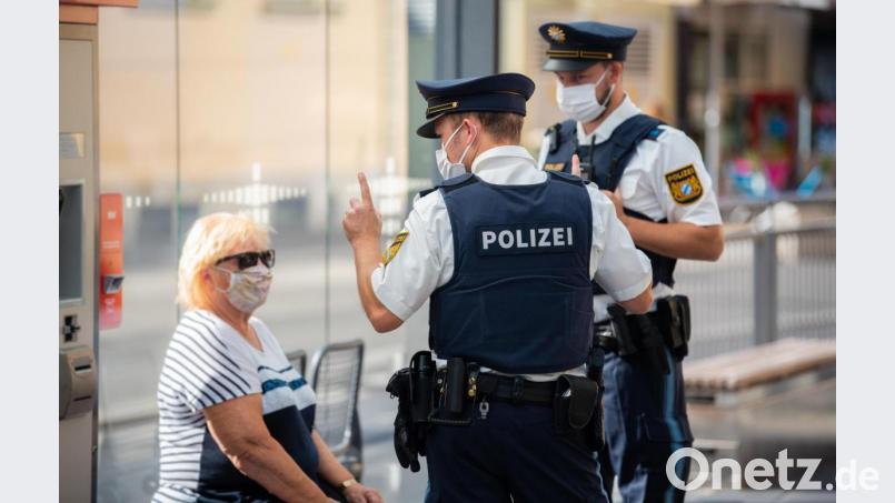 Zwei Polizisten nehmen an einer Haltestelle in Würzburg von einer Frau nach einem Verstoß gegen die Maskenpflicht im öffentlichen Nahverkehr die Personalien auf. So ähnlich ging es einem 27-Jährigen am Schwandorfer Busbahnhof. Symbolbild: Nicolas Armer/dpa