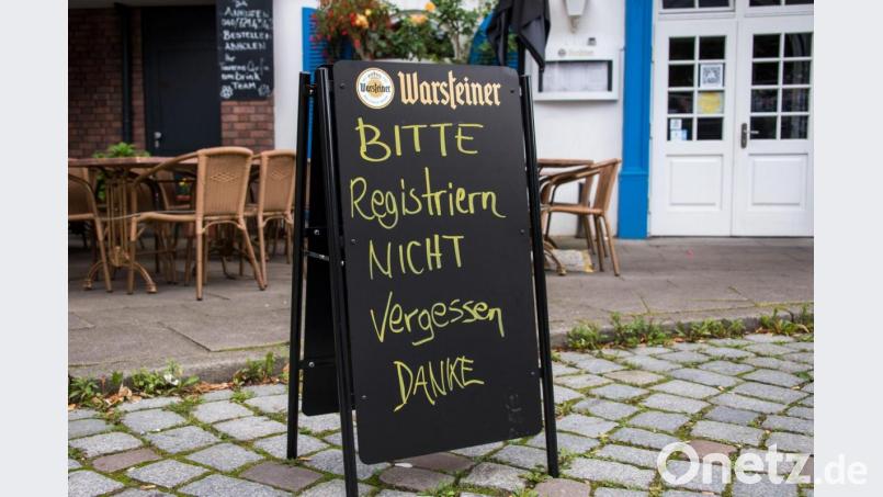 Eine Tafel mit der Aufschrift "Bitte Registrieren nicht vergessen. Danke" steht vor einem Restaurant. Bild: Daniel Bockwoldt/dpa
