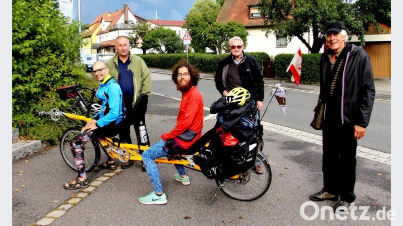 Malte Boßert und Tilmann Jiménez Reichow machen mit ihrem Liegetandem halt in Neukirchen (von links). Zur Begrüßung stehen (von links) Zweiter Bürgermeister Christian Sperber, Erich Neumüller und Kreisheimatpfleger Walter Schraml bereit. Bild: ds