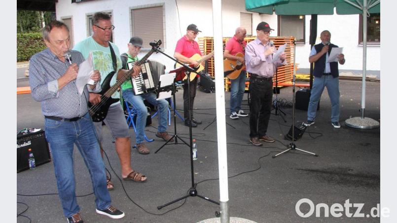 Mit einer Gesangseinlage überraschten Josef Zöllner (links), Gerhard Weber und Josef Daubenmerkl (von rechts). Im Hintergrund die Band „Viertakter“. Bild: wro