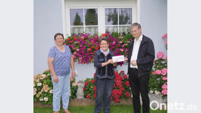 Der Waldthurner Pfarrer Norbert Götz und dessen „Pfarrköchin“ Elisabeth Kodalle (links) freuen sich im Garten von Christa Wildenauer über 1000 Euro für die Renovierung der Rosenkranzstationen zum Fahrenberg. Bild: fvo