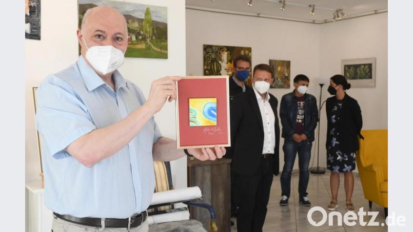 Der Kurator und Veranstalter der Vernissage &quot;Kunst hilft Menschen&quot; Wladimir Galperin (links) präsentiert ein zu erwerbendes Kunstwerk. mit (von links) Oberbürgermeister Jens Meyer, Thomas Schiller vom THW Weiden, Künstler Wladislaw Galben und Andrea Schild-Janker vom Stadtmarketing Weiden. Bild: Gabi Schönberger