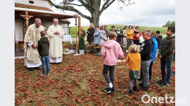 Domkapitular Johann Ammer spricht bei der Kindersegnung mit jedem einzelnen Kind ein paar freundliche Worte. Rechts von ihm Diakon Dieter Gerstacker; im Hintergrund der Kirchenchor Vilseck. Bild: rha