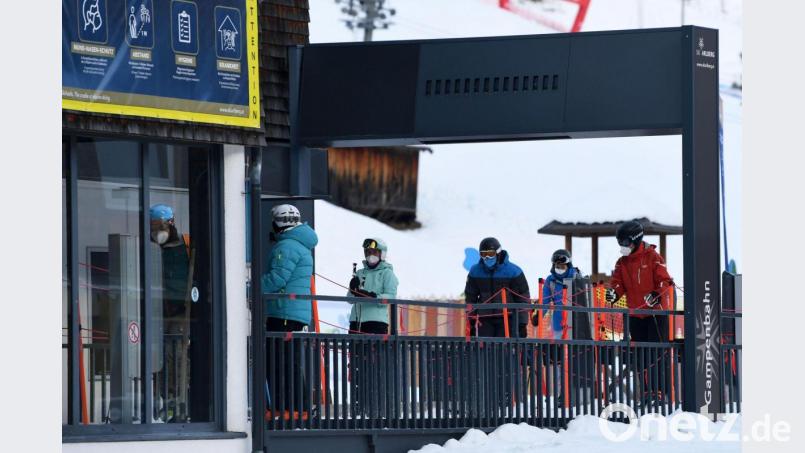 Wintersportler stehen in Tirol mit Mund-Nasen-Schutz an einem Skilift Schlange. Bild: Helmut Fohringer/APA/dpa