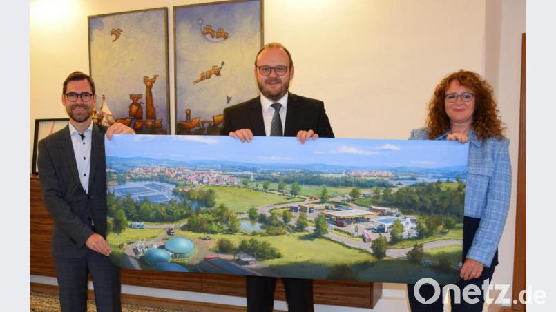Prof. Raphael Lechner (OTH), Landrat Andreas Meier und Barbara Mädl (von links) freuen sich über den nächsten Schritt des Landkreises zur Wasserstoffregion. Die Illustration zeigt keinen bestimmten Ort in NEW, sondern eine Szenerie, wie Anwendungsmöglichkeiten von Wasserstoff hier aussehen könnten, z. B. eine Wasserstofftankstelle mit Bussen, BAXI, Müllfahrzeugen etc. Bild: exb/Claudia Prößl