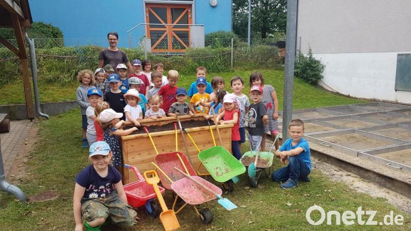 Mit Schubkarren und Schaufeln unterstützten die Kinder tatkräftig Jürgen Huber (hinten) beim Befüllen der Hochbeete. Bild: ibj