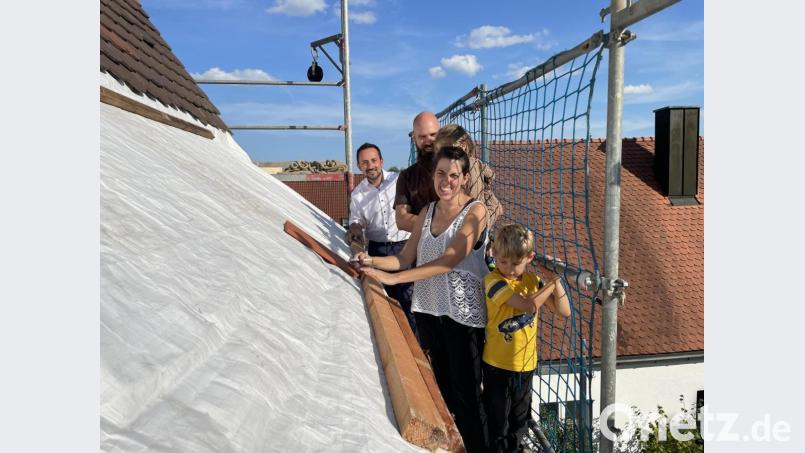 Pfarrer Stefan Fischer (links) mit der Pfarrfamilie Scherf aus Amberg beim Signieren der Ziegel in luftiger Höhe auf dem Kirchendach in Hirschau. Bild: wku