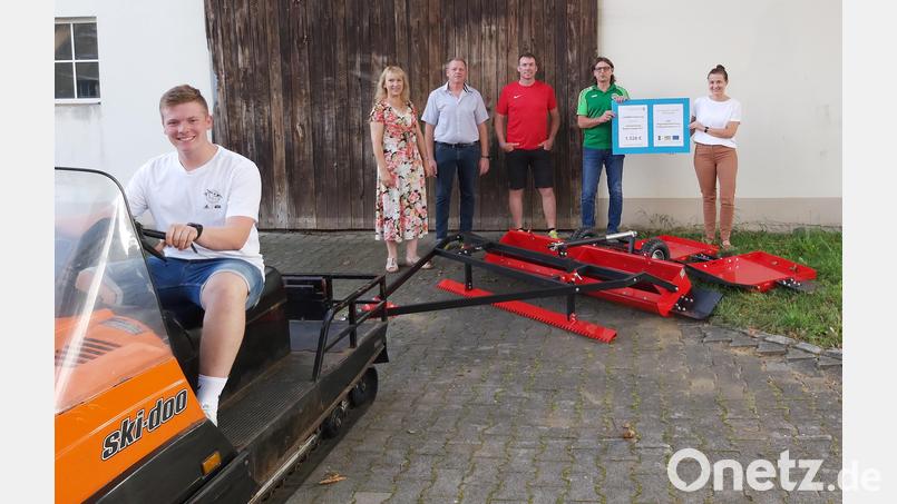 Auf dem Motorschlitten sitzt Noah Graf, hinter dem neuen Spurgerät stehen (von links) Bürgermeisterin Brigitte Bachmann, Zweiter ASV-Vorsitzender Thomas Nitzbon, &quot;Loipenflüsterer&quot; Helmut Graf, ASV-Vorsitzender Thomas Melzer und Veronika Schmalzl von der LAG Regionalentwicklung Amberg-Sulzbach. Bild: ASV Schwend/exb