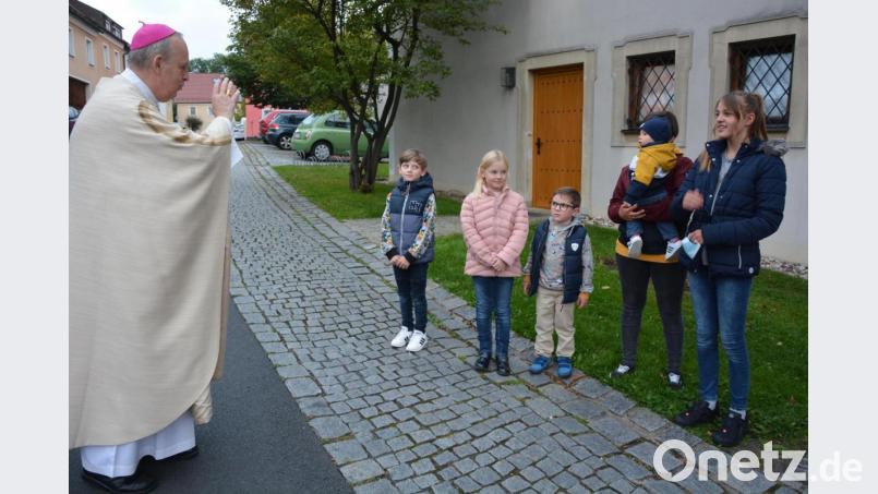 Weihbischof Reinhard Pappenberger segnete vor dem Einzug in die Pfarrkirche einige Kinder, die auf ihn gewartet hatten. Bild: jr