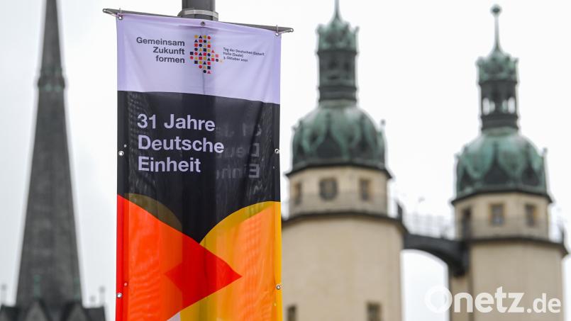 Ein Banner mit der Aufschrift &quot;31 Jahre Deutsche Einheit&quot; hängt vor den Türmen der Marktkirche &quot;Unser Lieben Frauen&quot; in Halle (Saale). In der Stadt finden in diesem Jahr die zentralen Feierlichkeiten zum Tag der Deutschen Einheit statt. Bild: Hendrik Schmidt