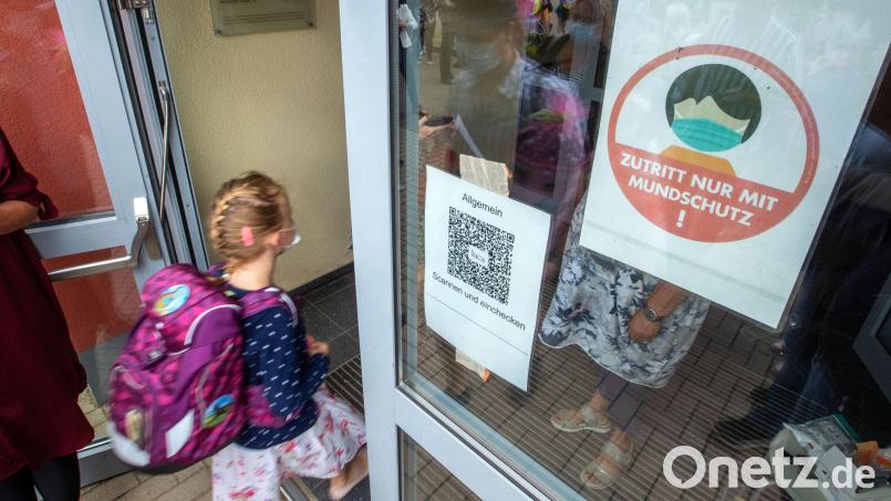 Schulanfänger und ihre Eltern gehen nach Corona-Kontrollen und mit Mund-Nasen-Schutz zur Einschulungsfeier in Schwerin. Symbolbild: Jens Büttner/dpa