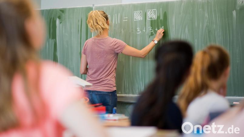 Eine junge Lehrerin schreibt im Mathematikunterricht an eine Schultafel . Symbolbild: Julian Stratenschulte/dpa