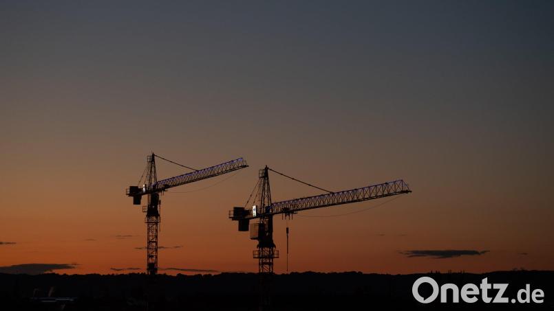 Kräne stehen vor dem Abendhimmel auf einer Baustelle. Symbolbild: Robert Michael/dpa
