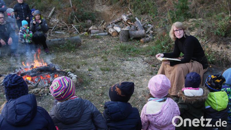 Gespannt warteten die Kinder und Erwachsenen auf den Start der Fackelwanderung. Zuvor aber blätterte Angelina Autsch in ihren Sagen- und Geschichtenbüchern. Bild: wro