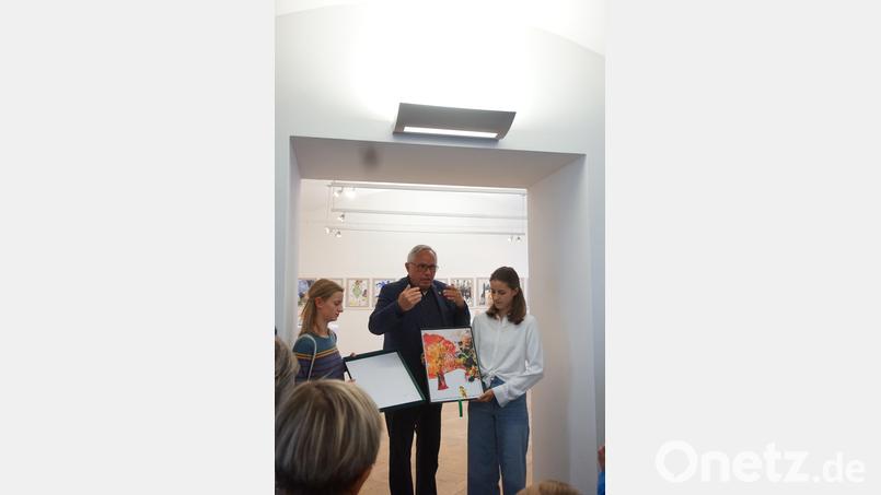 Die Collage mit dem roten Punkt, aus dem ein Baum wird. Jürgen Huber eingerahmt von Mathilda Jahn (links) und Emma Zembacher, die sich die Texte zu den Bildern als Erstlektorinnen vorgenommen haben. Bild: eib