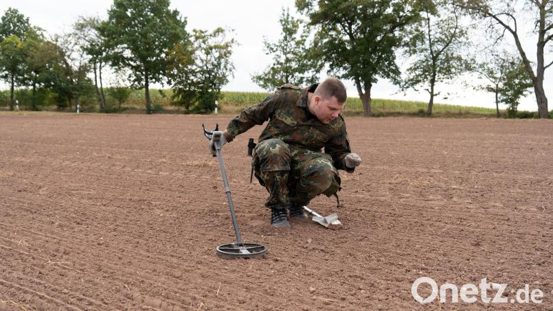 Daniel Scharnagl begutachtet auf einem Feld bei Neunkirchen einen der Funde, den sein Metalldetektor im Boden angezeigt hat. Bild: Martin Zimmer