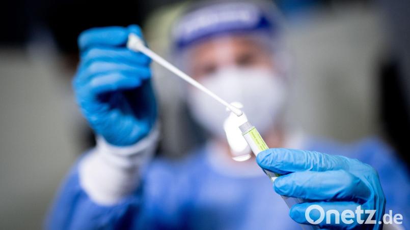 Eine Mitarbeiterin hält in einem Covid-19-Testcenter die Probe von einem Rachenabstrich in den Händen. Symbolbild: Matthias Balk/dpa