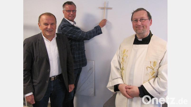 Ortssprecher Hans Scharl, Bürgermeister Hermann Falk und Pfarrvikar Christian Preitschaft bringen im neuen Gemeinschaftshaus von Burgstall das von der Stadt Hirschau gestiftete Kreuz an. Bild: fg