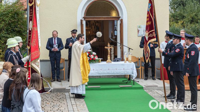 Pfarrer Dominik Mitterer weiht die neue Fahne der Feuerwehr Traßlberg im Festgottesdienst zum 120-jährigen Bestehen der Dorfkapelle. Bild: chl