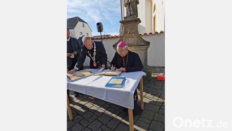 Erzbischof Ludwig Schick trägt sich ins Goldene Buch ein. Bild: hzi