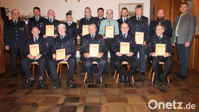 Vorsitzender Josef Völkl (stehend, links) und Bürgermeister Rainer Rewitzer (stehend, rechts) freuen sich mit den ausgezeichneten Feuerwehrkameraden. Bild: pi