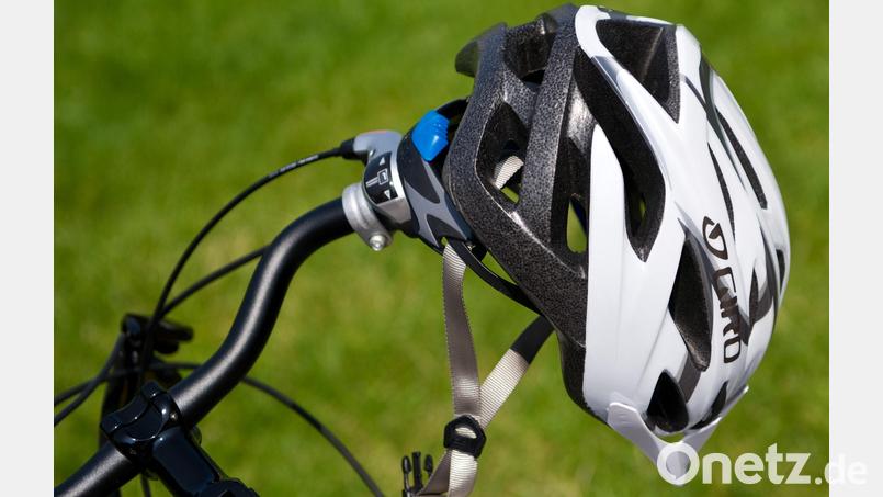 Ein Fahrradhelm hängt an einem Lenker. Bild: Daniel Bockwoldt/dpa