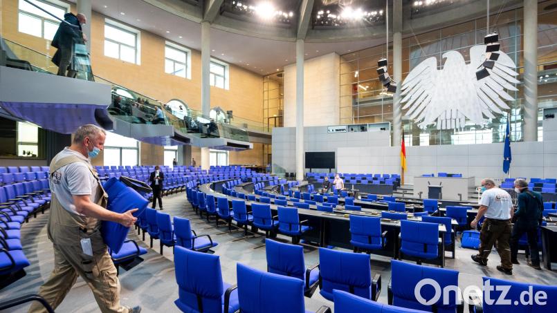 Ein Handwerker trägt einen Tisch im Plenarsaal während des Umbaus für die konstituierende Sitzung des 20. Deutschen Bundestags. Inzwischen sitzen 736 Abgeordnete im deutschen Parlament. Archivbild: Monika Skolimowska/dpa