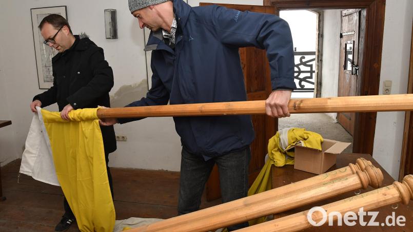 Mesner Thomas Pesold (rechts) und Pfarrer Thomas Helm ziehen in der Türmerstube der Basilika die Stoffahnen auf die alten Holzstangen, mit denen sie dann draußen am Turm befestigt werden. Bild: Petra Hartl