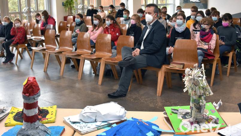 Circa 50 Fünftklässler lauschten am Lesenachmittag den Vorlesern. Die Preise im Vordergrund haben sie aus aussortierten Schulbüchern selbst gebastelt. Seminarleiter Ludwig Nerb (erste Reihe) ist als Betreuer des P-Seminars Bibliotheksmanagment für die Benotung der Abiturienten zuständig. Bild: Stephan Huber