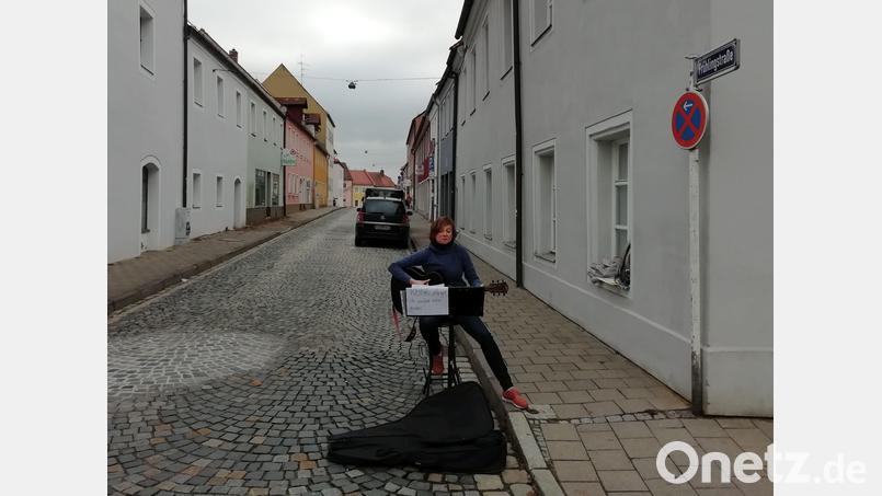 Daniela Ludwig sitzt am Eingang der Frühlingsstraße und macht mit einer Gitarren-Einlage darauf aufmerksam, dass es auch in dieser Nebenstraße Geschäfte gibt, die am verkaufsoffenen Sonntag offen haben - von den meisten Passanten aber ignoriert werden. Bild: Gräf