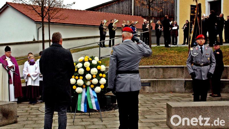 Bürgermeister Dietmar Schaller gedachte mit zahlreichen Bürgern in einer würdevollen Feier am Mahnmal vor der Marienkirche der Gefallenen beider Weltkriege und schlossen die jetzigen Opfer weltweit mit ein. Im Vordergrund das Niederlegen des Kranzes, im Hintergrund der Pfarrer und die Blaskapelle. Bild: zer