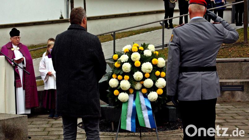 Bürgermeister Dietmar Schaller gedachte mit zahlreichen Bürgern in einer würdevollen Feier am Mahnmal vor der Marienkirche der Gefallenen beider Weltkriege und schlossen die jetzigen Opfer weltweit mit ein. Im Vordergrund das Niederlegen des Kranzes, im Hintergrund der Pfarrer und die Blaskapelle. Bild: zer