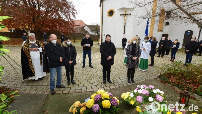 Nach der Kranzniederlegung verharren Bürgermeister Sebastian Hartl, Zweite Bürgermeisterin Sigird Ziegler, die Vertreter des VdK-Ortsverbandes Luhe und Pfarrer Arnold Pirner noch zu einer Gedenkminute. Im Hintergrund verliest Norbert Wildenauer Gedenkworte der Soldaten- und Reservistenkameradschaft Luhe. Bild: bey