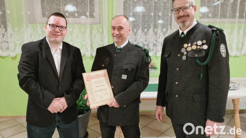 Schützenmeister Manuel Stich (links) und Christian Behr (rechts) übergeben Ehrenschützenmeister Jürgen Merkl (Mitte) die Urkunde. Bild: adj