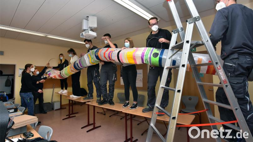 Die beteiligten Schülerinnen der Dr.-Johanna-Decker-Schulen und Azubis der Firma Baumann befestigen gemeinsam das Hauptrohr der Lüftungsanlage an der Klassenzimmerdecke. Bild: Stephan Huber