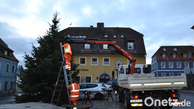 Karl Koller und Christian Scherer vom Bauhof des Marktes Moosbach haben einen schmucken Weihnachtsbaum am Marktplatz aufgestellt und verankert. Auch die Lichter sind schon angebracht. Heuer erstmals durch eine Hebebühne. Bild: gi