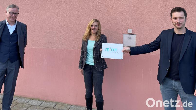 Ein &quot;MINT-Schild&quot; wird künftig an der Fassade des Gymnasiums an eine Schule mit vielen zukunftsorientierten Fächern erinnern. Schulleiter Harald Olschner, Fachschaftsleiterin Katja Hagen und Fachschaftsleiter Alexander Schatz (von links) freuen sich über die Auszeichnung. Bild: do