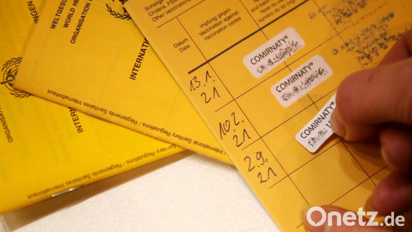 Eine Arzthelferin klebt den Nachweis einer dritten Impfung mit dem Corona-Impfstoff Comirnaty von Biontech/Pfizer gegen das Corona-Virus in ein Impfbuch. Von Mittwoch auf Donnerstag (25. November) verzeichnete das RKI in seiner Statistik für Amberg und Amberg-Sulzbach 265 Neuinfektionen. Symbolbild: Wolfgang Kumm / dpa