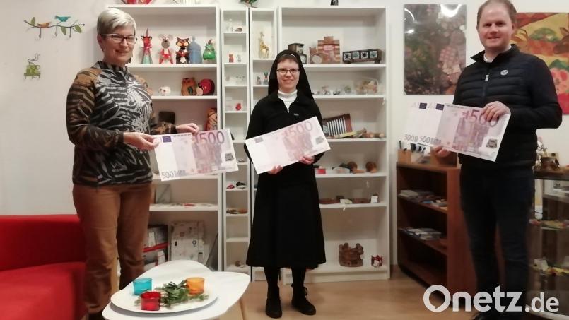 Marianne Zeiser (links) und Stadtpfarrer Stefan Wagner (rechts) übergeben die Spende an Schwester Christine Gindhart (Mitte). Bild: Gaby Reiml/exb