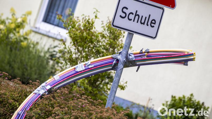 Leerrohre mit unterschiedlichen Durchmessern und Farben für das spätere Einblasen von Glasfaserkabeln hängen an einer Baustelle für den Breitband-Internetausbau für eine Schule. Bild: Jens Büttner/dpa