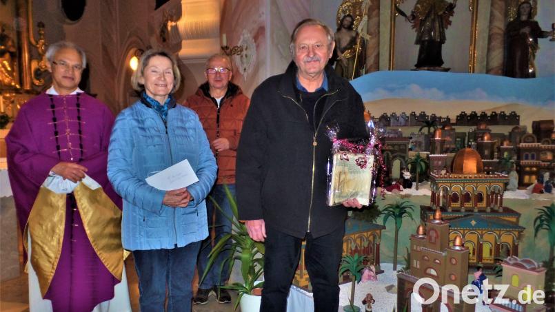 Gunda und Friedrich Hermann freuen sich über das Lob und ein kleines Geschenk von Pfarrer Varhese Puthenchira und Kirchenpfleger Leonhard Steinsdörfer (hinten, rechts). Seit 40 Jahren baut das Ehepaar die große Krippe in der Kirche auf. Bild: jml