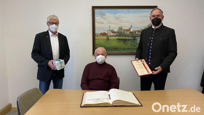 Bürgermeister Richard Kammerer (rechts) und Stellvertreter Johann Gurdan (links) überreichen die Ehrenamtsurkunde mit Geschenk an Werner Stocker (Mitte) und bitten um einen Eintrag ins Goldene Buch. Bild: knh