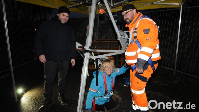 Zweite Bürgermeisterin Sigrid Ziegler wagt den Abstieg in den Untergrund, um sich ein Bild vom Umfang der Sanierungsarbeiten am Oberwildenauer Regenrückhaltebecken zu machen. Bürgermeister Sebastian Hartl (links) fungiert als Helfer auf der Baustelle. Bild: bey