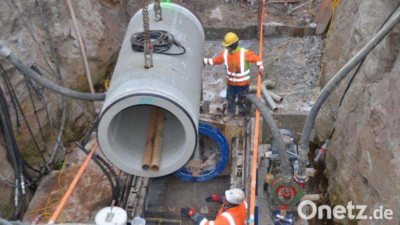 Ein neues Stahlbetonrohr wird per Autokran in den Vorschubrahmen gehoben. Für das Bohrgerät sind in der rund sieben Meter tiefen Baugrube eine Bodenplatte und eine Stützwand betoniert worden. Bild: ak
