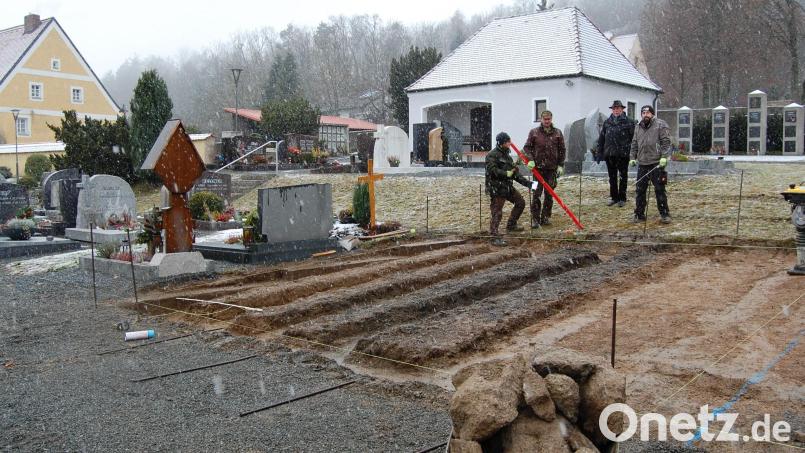 Die Pfarrei Michldorf kann für Urnenbeisetzungen auch weiterhin verschiedene Möglichkeiten anbieten, meint Pfarrer Alfons Forster (Zweiter von rechts). Neben der Urnenwand (im Bild links neben dem Leichenhaus), den Urnenstelen (rechts vom Leichenhaus) und Urnengräbern im alten Friedhof werden nun 24 Plätze für Urnengräber im neuen Friedhof errichtet. Bild: grm
