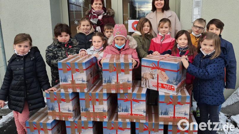 Einige Kinder der Zweiten Klassen präsentieren die insgesamt zwölf Pakete, die für die Weihnachtstrucker-Aktion der Johanniter bereitgestellt wurden. Mit im Bild Elternbeiratsvorsitzende Carola Wölfl und Grundschulleiterin Petra Andritzky (hinten, von links). Bild: Grundschule Mitterteich/exb