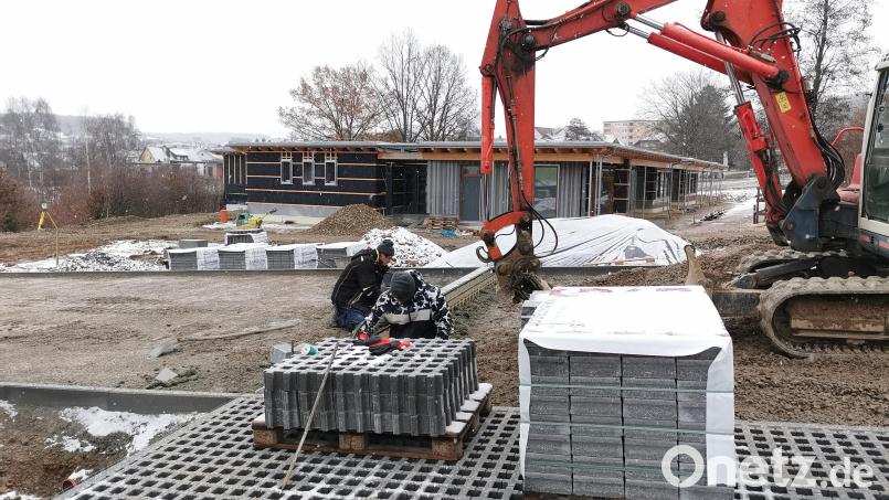 Am Zugangsbereich zum neuen Kinderhaus wird mit Hochdruck gearbeitet. Die Pflasterer der Firma Liegl-Bau aus Leuchtenberg verlegen die Rasengittersteine für die Parkbuchten. Bild: Portner