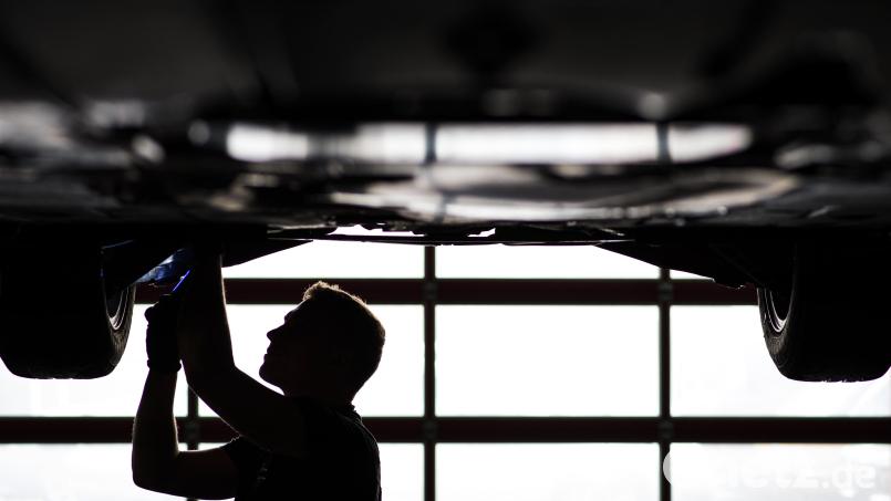 Ein Mechaniker arbeitet in einer Kfz-Werkstatt an der Unterseite eines Autos, das auf der Hebebühne steht. Symbolbild: David-Wolfgang Ebener